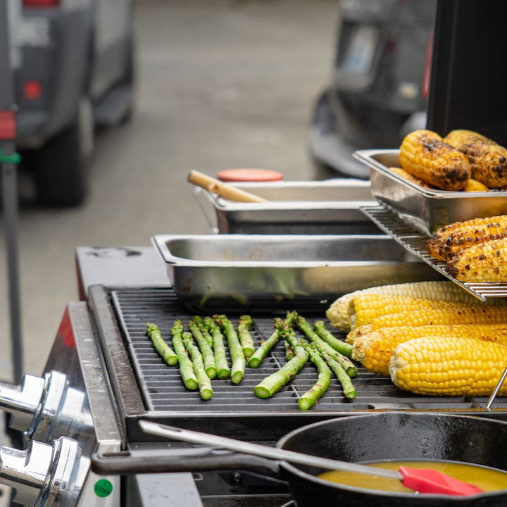 Baby asparagus and corn being prepared on a hot grill, from Sharbatly.