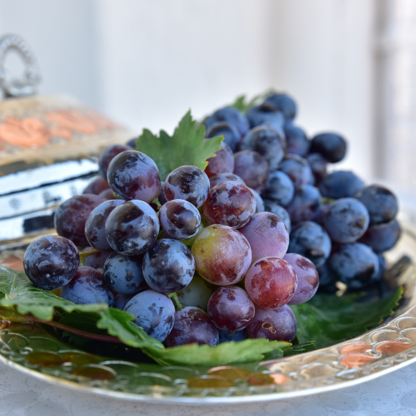 Black grapes in a 1 kg pack, fresh and plump, from Sharbatly, showing clusters of dark purple grapes on the vine.