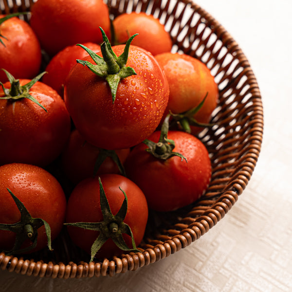 Fresh round organic tomatoes in a 1 kg pack from Naqwat Al Nana, displayed on a kitchen countertop.