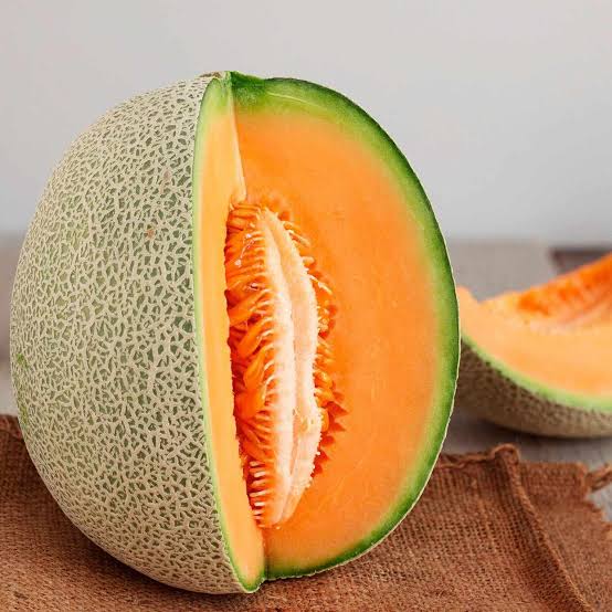 Single piece of fresh Holland cantaloupe melon, showcasing vibrant orange flesh and green rind on a white background.
