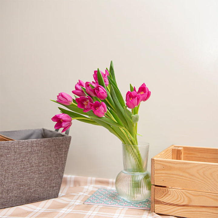 Fuchsia pink tulips from Fresh Flower Holland arranged in a bouquet, showcasing vibrant petals and green stems.