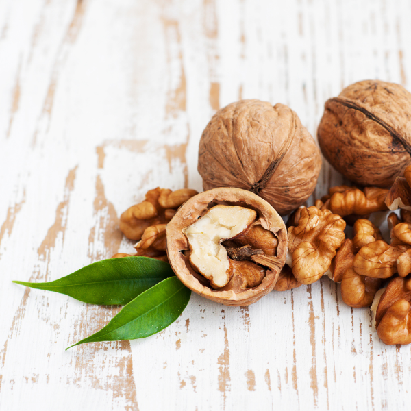 Raw walnuts in a 0.5 kg pack from Sharbatly, displayed in a clear container with some walnuts scattered around.