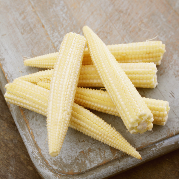 Fresh baby corn in a 0.1 kg pack from Thailand, showcasing small, tender corn cobs with green husks and bright yellow kernels.