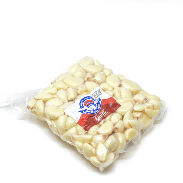 Peeled garlic cloves in a 0.45 kg pack from Sharbatly, fresh vegetable with white garlic bulbs on a kitchen surface.