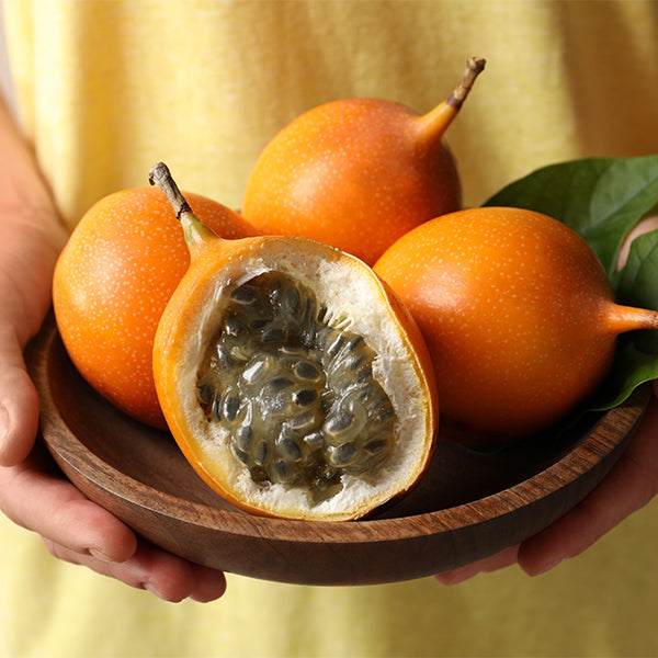 Holland granadilla fruit, 0.5 kg, vibrant orange exterior with leafy green stem on a white background.