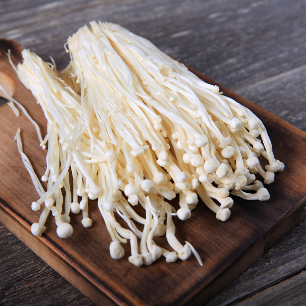 Fresh Holland enoki mushrooms in a 0.1 kg vegetable pack, showcasing long, slender white mushrooms on a white background.