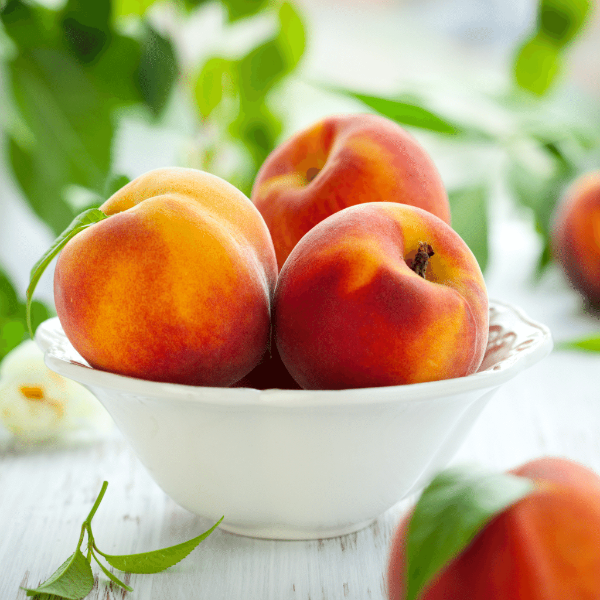Fresh Sharbatly peaches in a 1 kg pack, showcasing ripe, juicy fruit with vibrant orange and yellow skin on a white background.