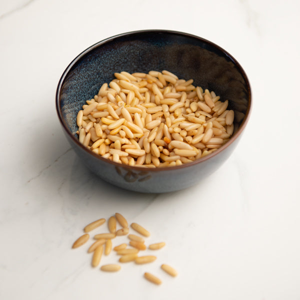 All-natural pine nuts in a 0.1 kg pack from Fresh Nuts, showing a close-up of light tan pine nuts on a white background.