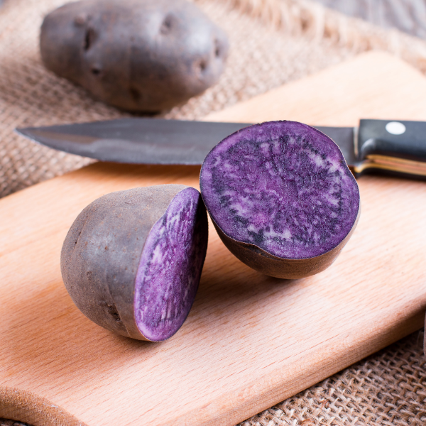 Holland Vitelotte purple potatoes in a 1 kg pack, fresh and unwashed, showcasing their vibrant purple skin and round shape.