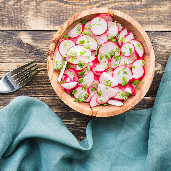 Fresh red radishes in a Holland vegetable pack, showing vibrant bulbous roots with green leafy tops.