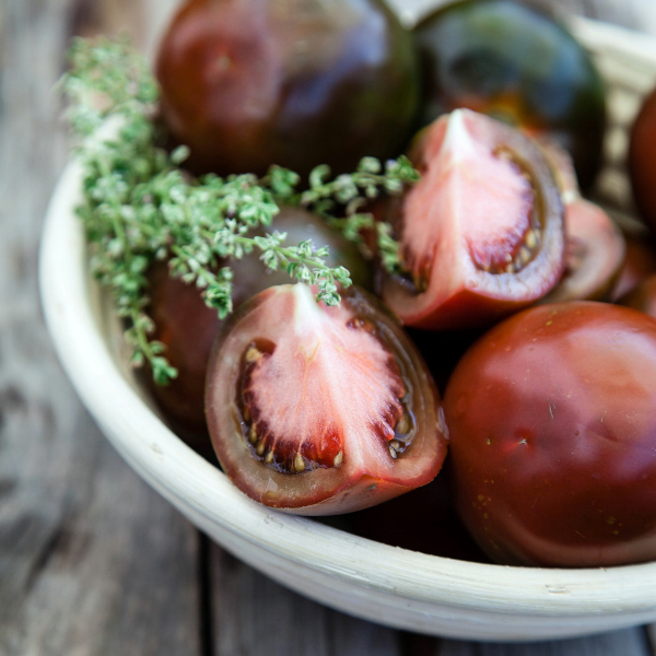 Fresh Kumato tomatoes from Holland in a 0.5 kg vegetable pack, showcasing ripe, dark red tomatoes with smooth skin.