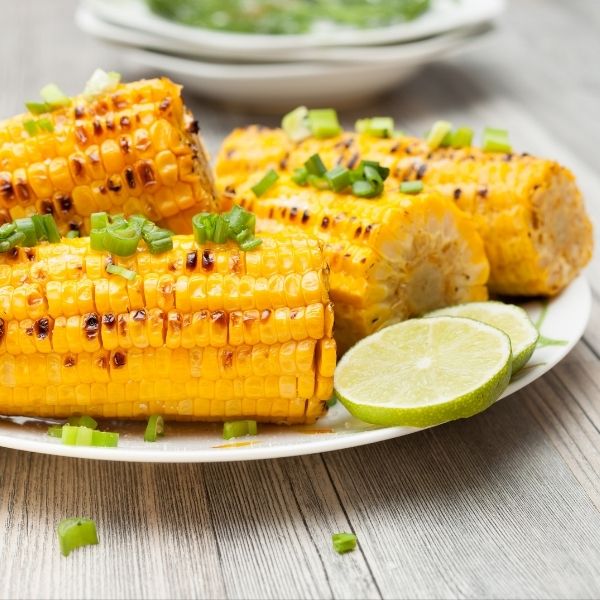 Fresh yellow corn on the cob from Local Market, close-up view showing vibrant kernels and green husk.